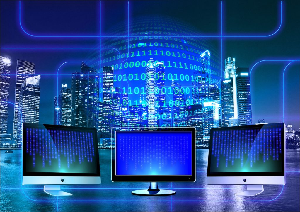 Futuristic graphic with skyscrapers in the background, a sphere of binary in the middle and computers with binary on the screens. 